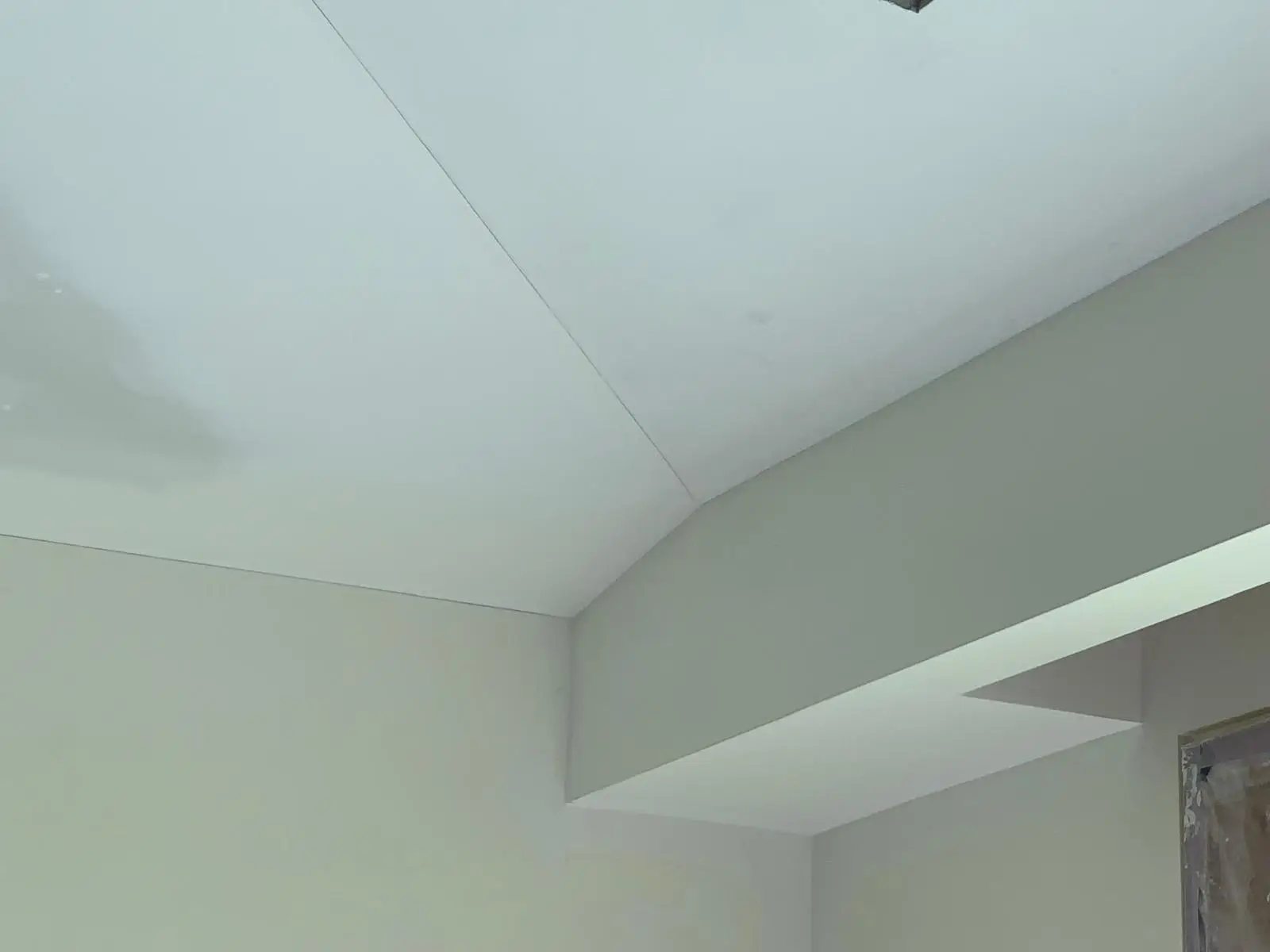 Sloped ceiling plane meeting a dropped bulkhead at a clean arris, finished in drywall.