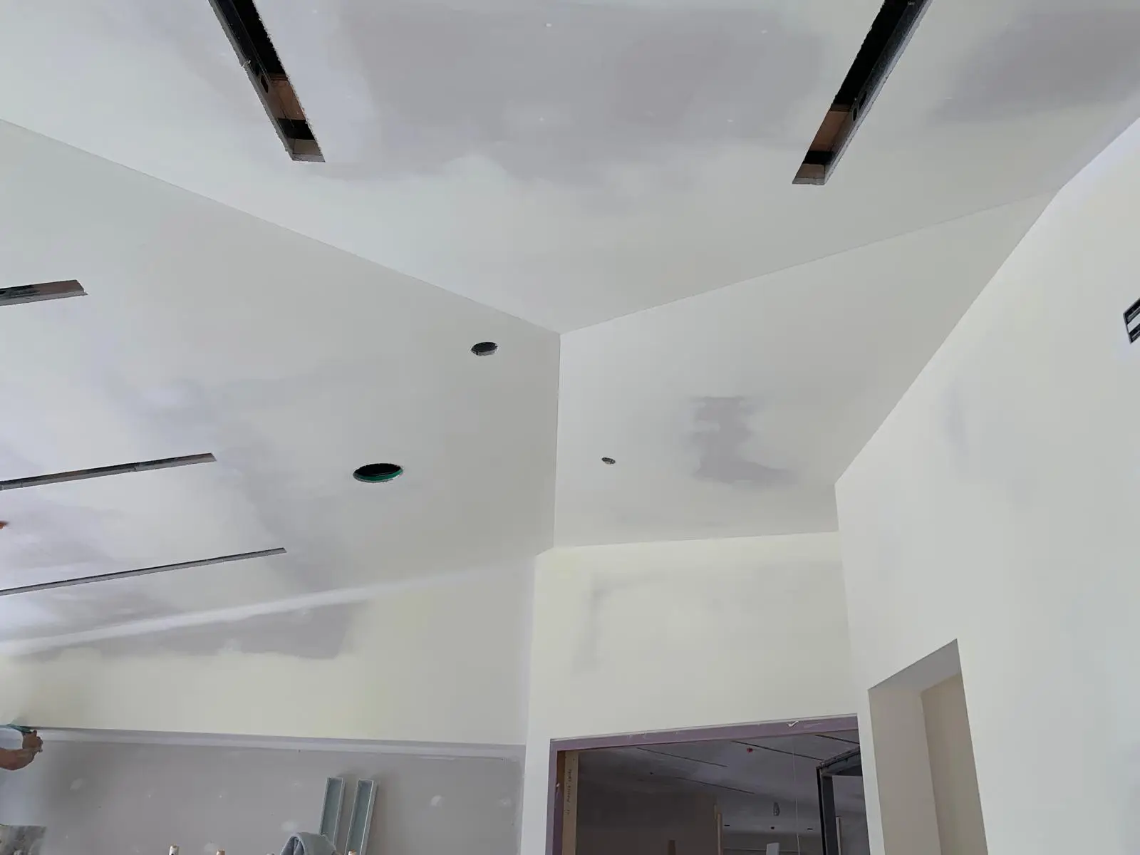 Stepped ceiling planes with linear diffuser slots and pot-light cutouts, taped and coated.