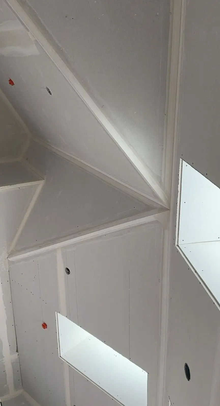 The same ceiling corner boarded: sheets hung, joints and screw lines still showing, bead set but untaped.