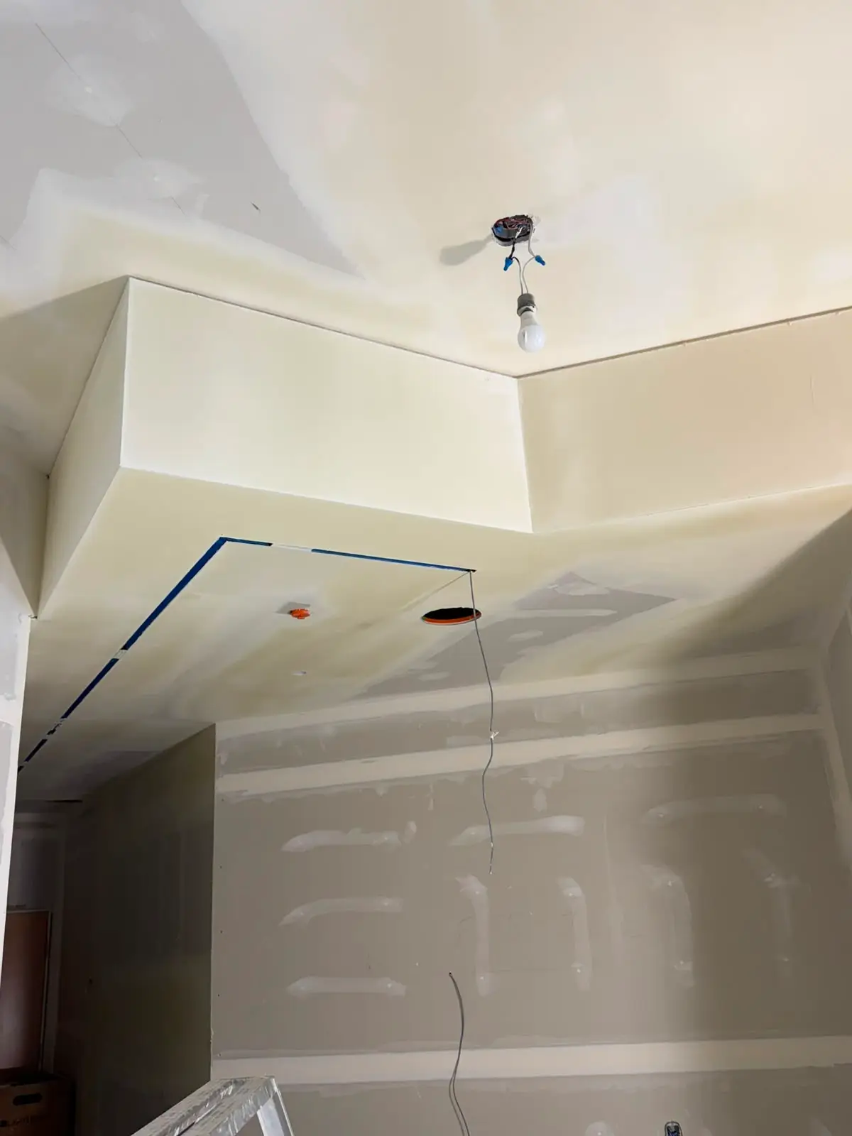 Dropped bulkhead returning around a room above a taped and coated wall.