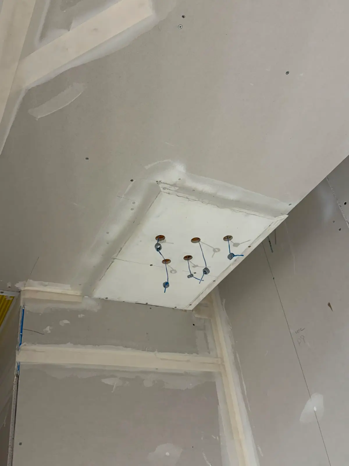 Recessed light box framed and boarded into a sloped ceiling, six fittings wired and waiting.