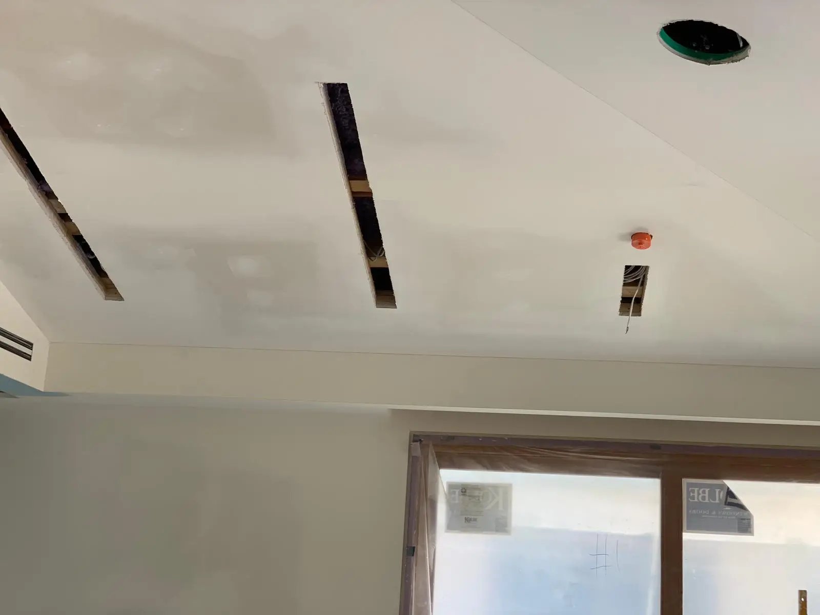 Coated tray ceiling with linear slot openings cut through it and a bulkhead over a slider.