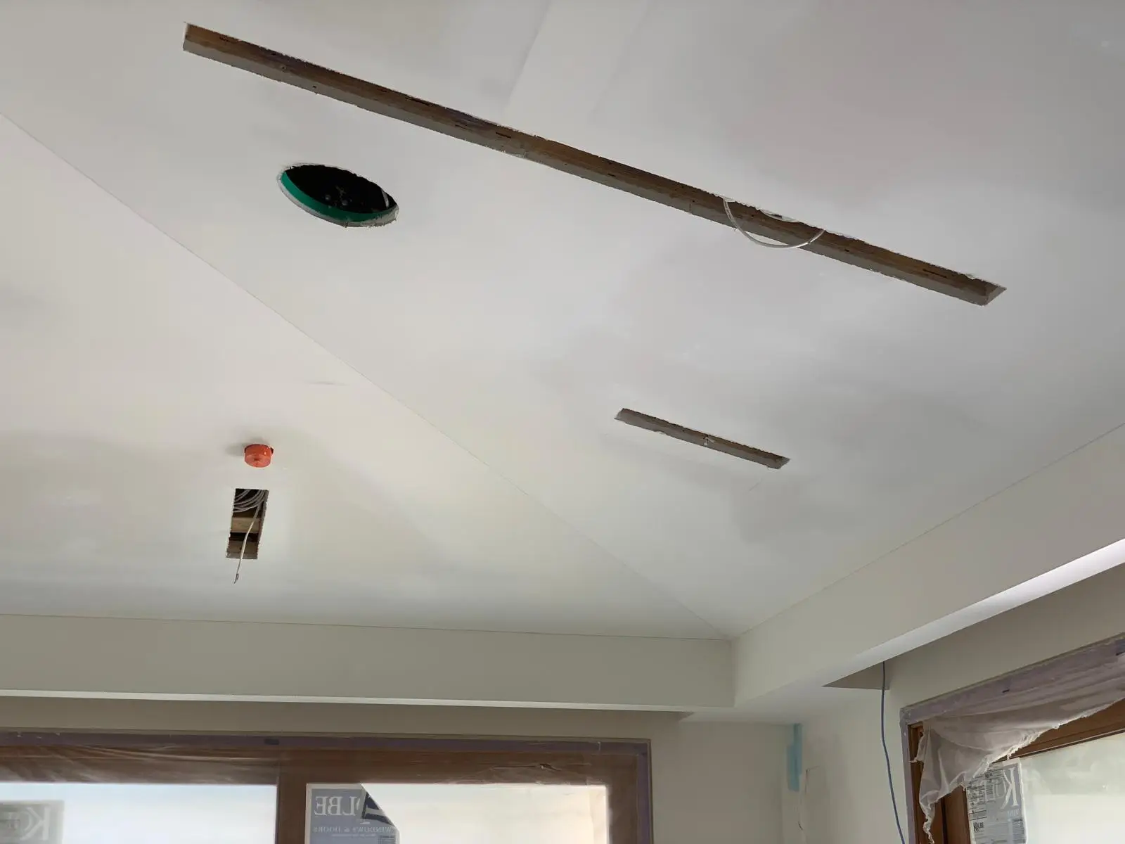 Tray ceiling with a long linear service slot, a pot-light cutout and a fan box, taped and coated.